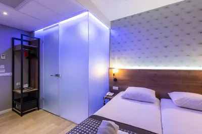a bedroom with a white bed and a blue wall at Melrose Hotel in Amsterdam