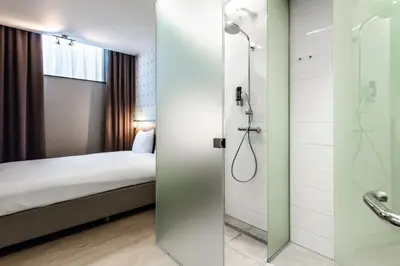 a hotel room with a shower and a bed at Melrose Hotel in Amsterdam