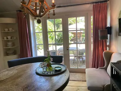 a living room with a wooden table in front of a door at De Schuilhoek Private Guesthouse in Blaricum