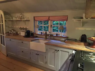 a kitchen with white cabinets and a sink at De Schuilhoek Private Guesthouse in Blaricum