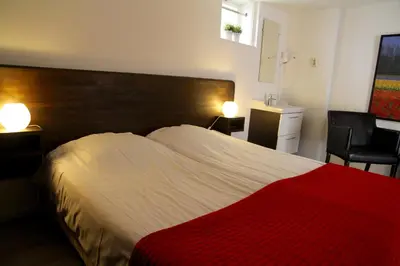 a bedroom with a large bed with a red blanket at budget rooms Doppenberg in Zandvoort