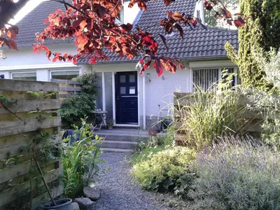 a white house with a black door and a fence at Casa Batavia B&B in Lelystad