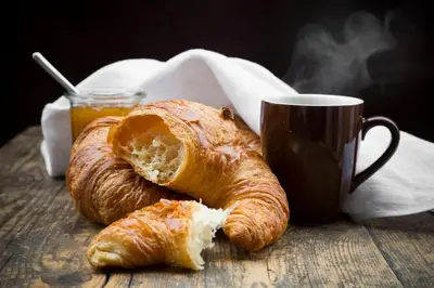 a table topped with croissants and a cup of coffee at Attic Monkeys Lodge in Amsterdam