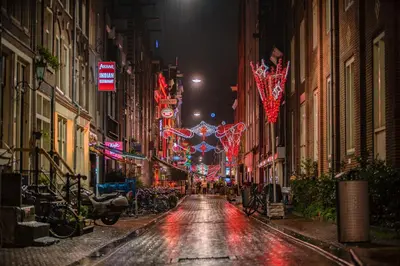 a wet city street at night with christmas lights at Leidse Square 5 star Luxury Apartment in Amsterdam