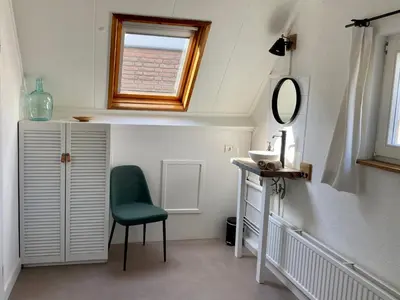 a bathroom with a green chair and a mirror at Zilt Noordwijk in Noordwijk aan Zee