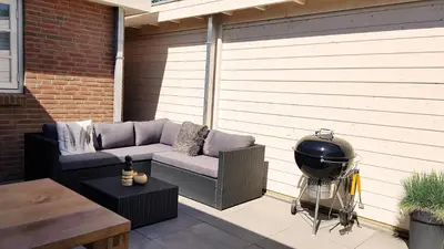 a patio with a couch and a helmet on it at INTIKA Beach House in Zandvoort