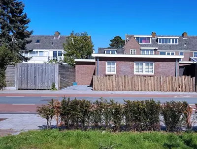a brick house with a wooden fence on a street at INTIKA Beach House in Zandvoort