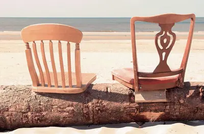 a chair sitting on a tree stump on the beach at INTIKA Beach House in Zandvoort