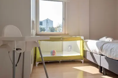 a childs bedroom with a crib and a window at Spacious Family Holiday Home (7p), Free indoor parking in Zandvoort