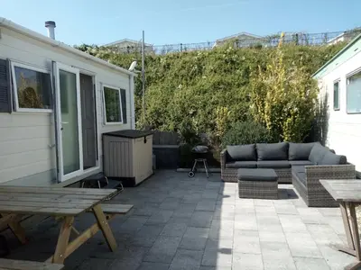 a patio with a couch and a table at CHALETS IN THE DUNES nearby the beach in IJmuiden