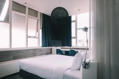 a bedroom with a white bed and two windows at Anne&Max Boutique Hotel in Utrecht