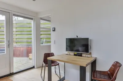 a room with a tv and a table and chairs at Modern Bungalow Zandvoortselaan in Zandvoort