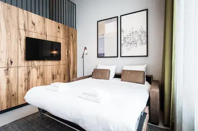 a bedroom with a large bed and a tv on a wall at YAYS Amsterdam East by Numa in Amsterdam