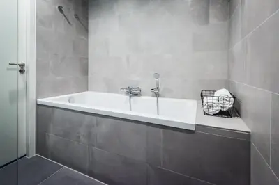 a white bath tub in a gray bathroom at YAYS Amsterdam East by Numa in Amsterdam