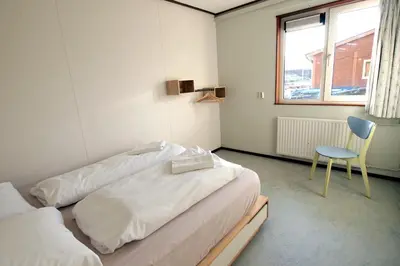 a room with two beds and a chair and a window at Amsterdam Farm Lodge in Amsterdam