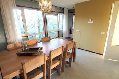 a dining room with a wooden table and some windows at Amsterdam Farm Lodge in Amsterdam