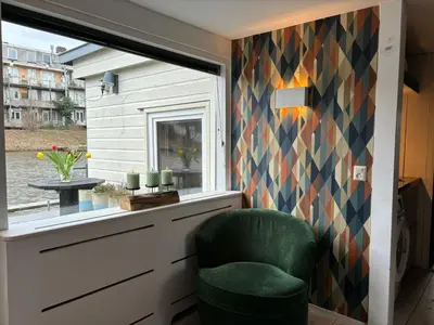 a room with a green chair and a window at Houseboat Amsterdam in Amsterdam