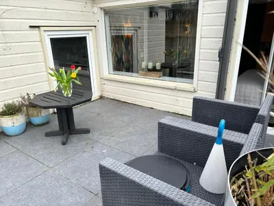 a patio with two chairs and a table with a vase on it at Houseboat Amsterdam in Amsterdam