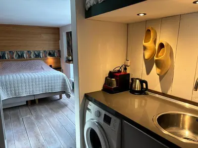 a room with a bed and a kitchen with a washing machine at Houseboat Amsterdam in Amsterdam