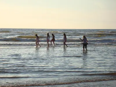 a group of women walking in the water on the beach at Hotel Rasch in Bergen aan Zee