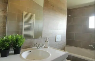 a bathroom with a sink and a tub and a mirror at Cozy Cottage in Warmenhuizen