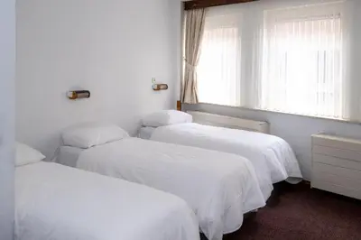 three beds in a room with white sheets and a window at Hotel Ben Centre in Amsterdam