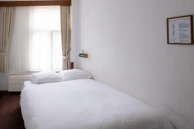 a white bed in a room with a window at Hotel Ben Centre in Amsterdam