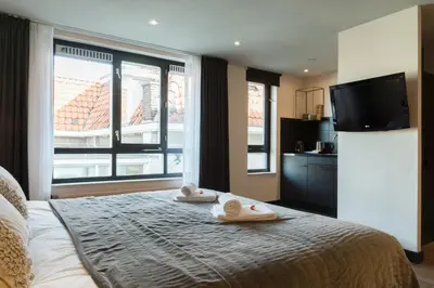 a bedroom with a bed with towels and a flat screen tv at Boutique Suites Lisse - Keukenhof in Lisse