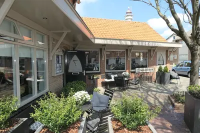 a patio with chairs and tables in front of a building at La Chatelaine in Egmond aan Zee