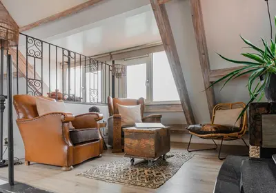 a living room with leather chairs and a staircase at La Chatelaine in Egmond aan Zee