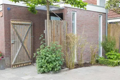 a brick house with a wooden gate and a fence at B&B Bike Studio Amsterdam in Amsterdam