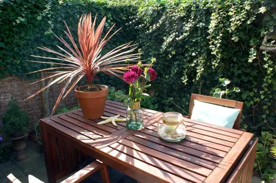 a wooden table with a vase of flowers on it at Egmond aan Zee Vakantiehuisje in Egmond aan Zee