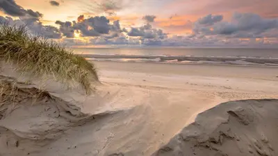 a beach with some sand and the ocean at Egmond aan Zee Vakantiehuisje in Egmond aan Zee