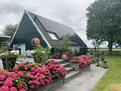 a house with a bunch of flowers in front of it at Vakantiehuis Het Uilennest in Wijdenes