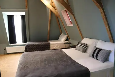 a room with two beds and a chair in it at Quentin Zoo Hotel in Amsterdam