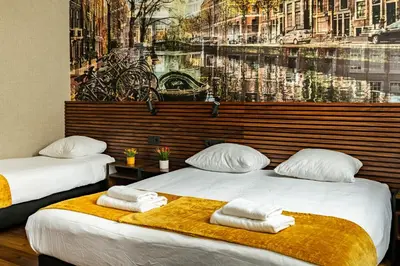 two beds in a room with a painting on the wall at Historic Centre Hotel in Amsterdam