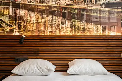 a bed with two pillows in front of a window at Historic Centre Hotel in Amsterdam