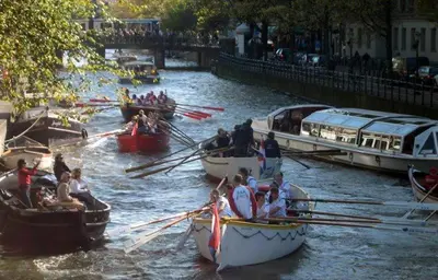 a group of people on boats in a river at The Posthoorn Amsterdam in Amsterdam