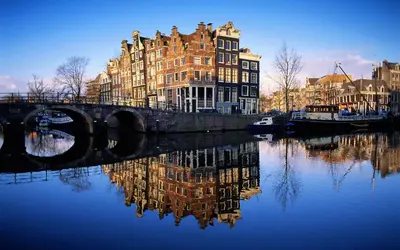 a bridge over a river with buildings and a city at Central & Quiet Canal Apartment in Amsterdam