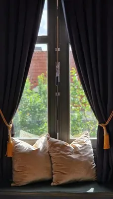 a pillow in front of a window with curtains at Canal House The Tannery Amsterdam in Amsterdam