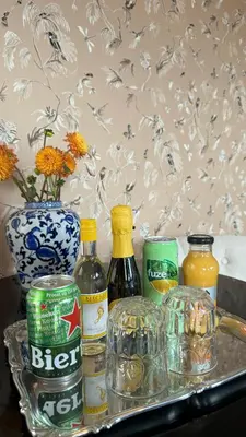 a tray with bottles of alcohol and a vase with flowers at Canal House The Tannery Amsterdam in Amsterdam