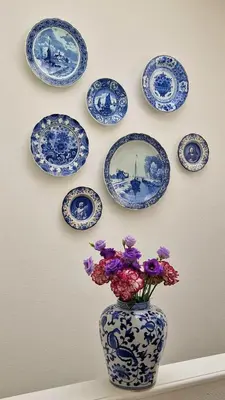 a vase with flowers on a wall with blue and white plates at Canal House The Tannery Amsterdam in Amsterdam