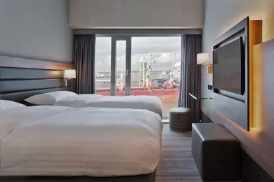 a hotel room with two beds and a flat screen tv at Moxy Amsterdam Houthavens in Amsterdam