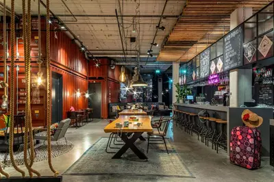 a restaurant with a table and chairs and a bar at Moxy Amsterdam Houthavens in Amsterdam