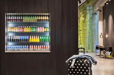 a display of soda bottles on a wall in a room at Moxy Amsterdam Houthavens in Amsterdam