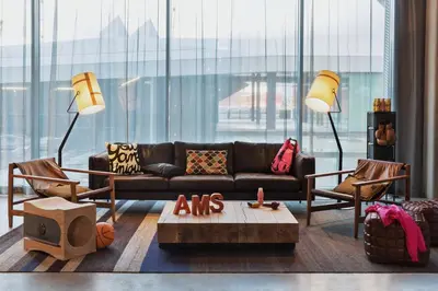 a living room with a couch and two chairs at Moxy Amsterdam Houthavens in Amsterdam