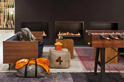 a room with a couch and a table and a fireplace at Moxy Amsterdam Houthavens in Amsterdam