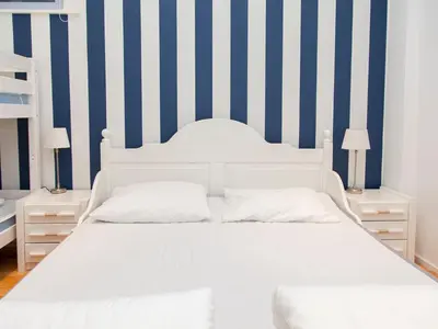 a white bed in a room with blue and white stripes at Appartementen Zandvoort in Zandvoort