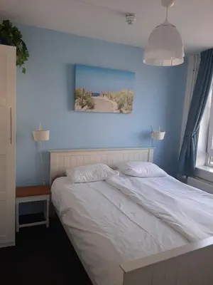 a bedroom with a white bed with a blue wall at Appartementen Zandvoort in Zandvoort