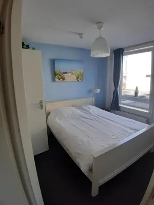 a bedroom with a white bed and a window at Appartementen Zandvoort in Zandvoort